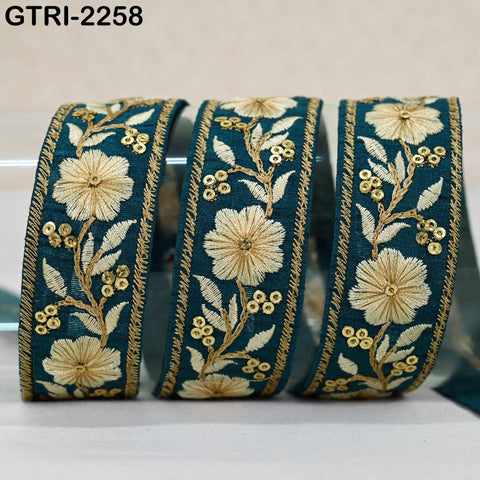 three decorative fabric pieces with intricate floral embroidery in shades of blue and gold. The pieces are arranged in a row, with the middle one being the largest and the other two being smaller in size.
