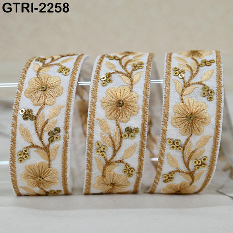 three white fabric ribbons with gold embroidered floral designs.