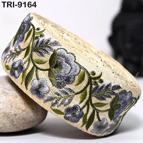 a decorative fabric with a floral pattern, including blue and green flowers and leaves, and a beige background.