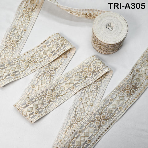 a roll of white, decorative fabric with a floral pattern, placed on a white surface.