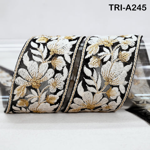 a decorative fabric with a floral pattern in black and white, featuring gold accents. The fabric appears to be a ribbon or a piece of cloth with a similar design.
