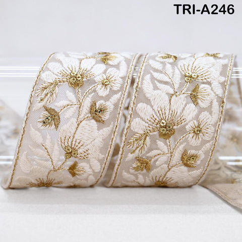 a decorative ribbon with a floral pattern, featuring gold embroidered flowers and leaves. The ribbon appears to be made of a light-colored material, possibly silk or chiffon, and is displayed against a white background.