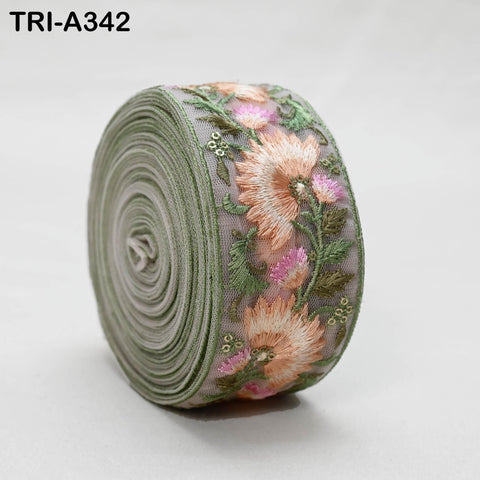 A close-up image of a decorative fabric with a floral pattern, featuring a green and pink color scheme.