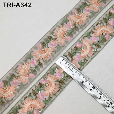 a decorative fabric with a floral pattern, including pink and green flowers, and a ruler placed on top of it.