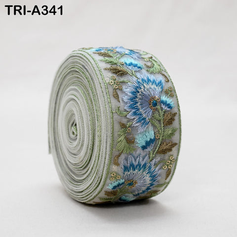 A close-up image of a decorative fabric with a floral pattern, featuring blue and green flowers and leaves.