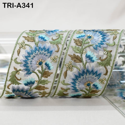 a decorative fabric with a floral pattern, including blue and green flowers and leaves. The fabric appears to be a decorative textile, possibly used for embellishment or as a decorative element.