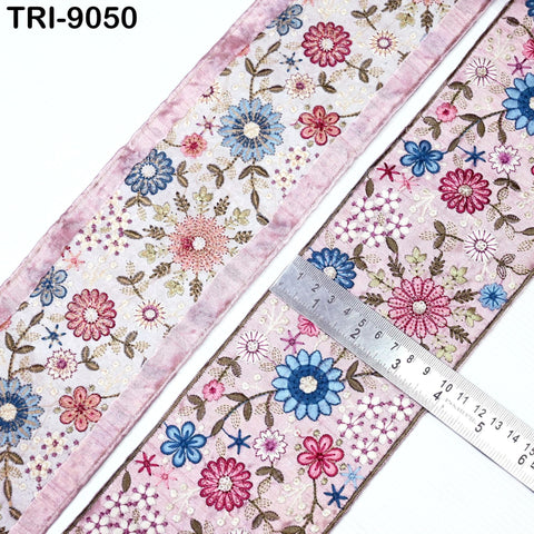 a close-up view of a decorative fabric with a floral pattern, featuring a pink border and a ruler for scale.