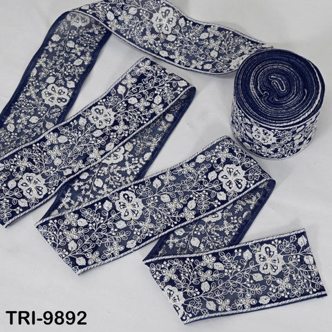 a collection of blue and white floral embroidered fabric pieces, including a roll of the same fabric and several individual pieces.