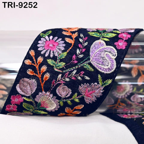 a close-up view of a decorative fabric with a floral pattern. The fabric appears to be black and is adorned with a variety of colorful flowers and leaves, creating a visually striking and intricate design.