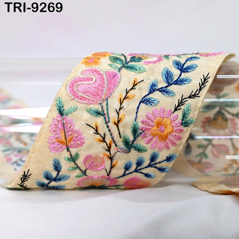 a close-up view of a decorative fabric with a floral pattern, including pink flowers, green leaves, and other colorful elements.