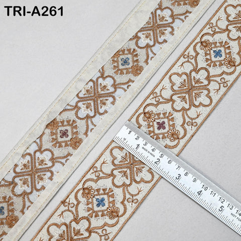 a close-up view of a decorative fabric with a repeating pattern of floral designs in shades of brown and white. A ruler is placed next to the fabric, indicating the size of the fabric.