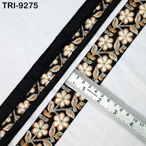 a close-up view of a decorative fabric with a floral pattern in black and gold colors. A ruler is placed next to the fabric, indicating the size of the fabric.