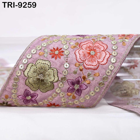 a decorative fabric with a floral pattern, including pink, green, and purple flowers, as well as small circular embellishments.