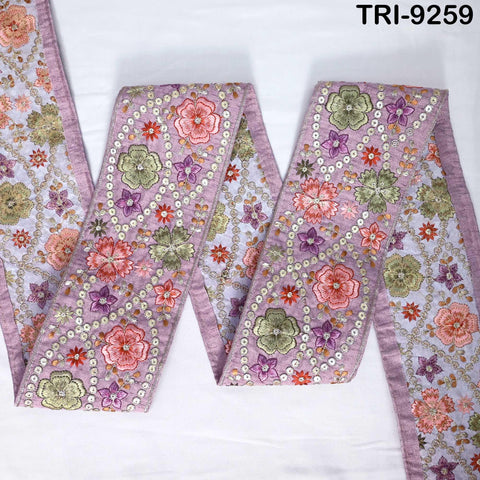 a decorative fabric with a floral pattern in shades of pink, green, and purple. The fabric appears to be a decorative textile, possibly used for clothing or home decor.