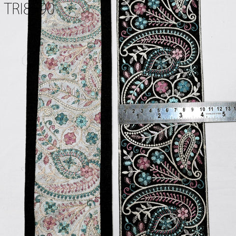 two pieces of fabric with intricate floral and paisley patterns, and a ruler is placed between them to measure the width of the fabric.
