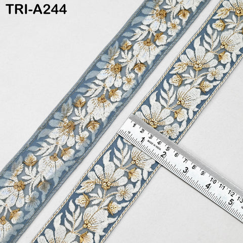 a close-up view of a decorative fabric with a floral pattern in shades of blue and gold. A ruler is placed on the fabric, indicating its size or dimensions.
