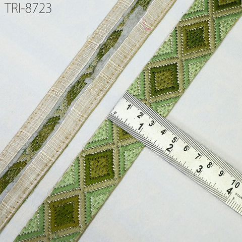 a close-up view of a decorative green and beige fabric with a ruler placed on it, indicating the size of the fabric.