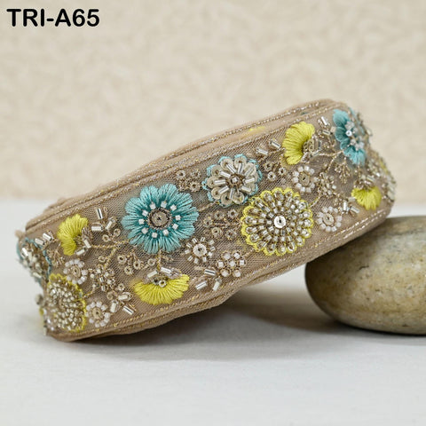 a decorative beaded belt with a floral pattern, including blue and yellow flowers, placed on a surface next to a rock.