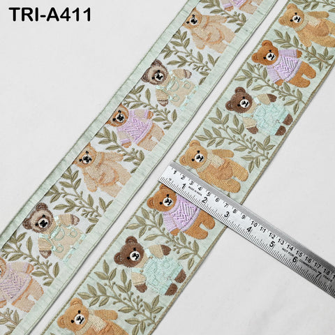 a decorative ribbon with a repeating pattern of teddy bears and leaves. The ribbon is placed on a white surface, and a ruler is visible, indicating that the ribbon is being measured.