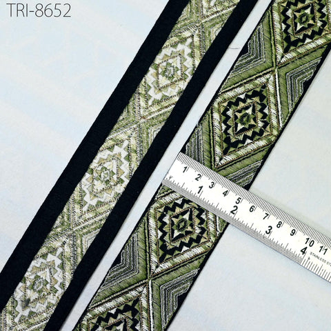 a decorative fabric with a repeating pattern of diamond shapes in shades of green and black, and a ruler placed next to it to measure the length of the fabric.