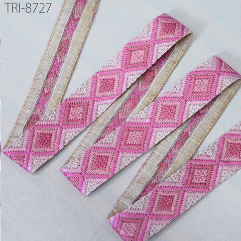 a collection of pink and beige embroidered fabric pieces arranged on a white background.