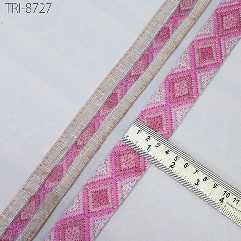 a close-up view of a pink and beige patterned ribbon, with a ruler placed on top of it to measure its length.