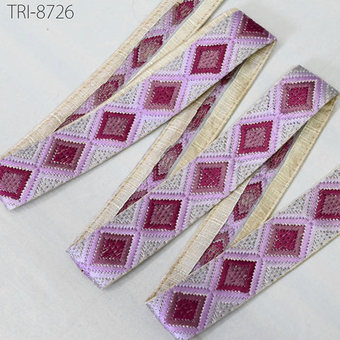 a collection of decorative fabric pieces with a repeating diamond pattern in shades of pink and white. The fabric appears to be made of a soft, textured material, possibly cotton or linen. The image does not contain any text or other discernible objects, and the focus is on the intricate diamond pattern on the fabric.