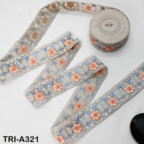 a collection of decorative fabric pieces, including a spool of embroidered fabric and several pieces of fabric with intricate floral patterns.