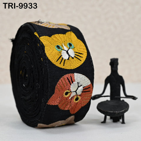 a black and orange cat-themed ribbon with a small black figurine of a person sitting next to it.