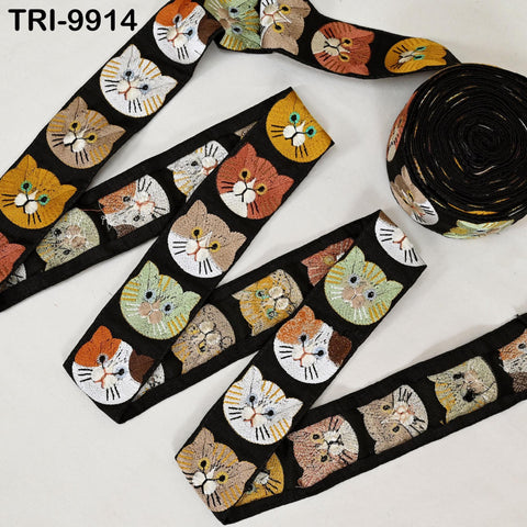 a collection of cat-themed fabric pieces, including a spool of black fabric with a repeating pattern of cat faces in various colors and sizes.