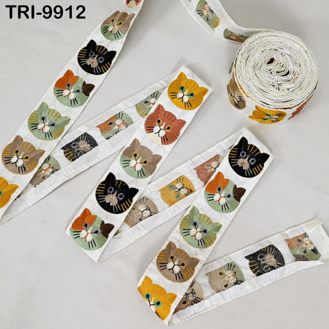 a collection of colorful cat-themed fabric pieces, including a spool of thread with a repeating pattern of cat faces and a spool of thread with a repeating pattern of cat faces.