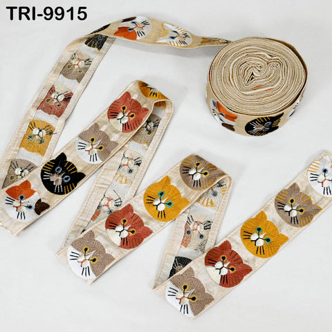 a collection of cat-themed fabric pieces, including a spool of thread with a repeating pattern of cat faces and a ribbon with a similar pattern.