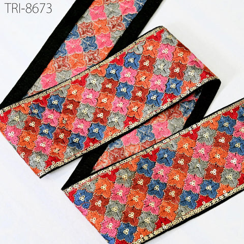 a decorative fabric with a floral pattern in various colors, including red, blue, and orange. The fabric appears to be a decorative trim or border, with a black border around the edges. The image does not contain any text or additional objects.