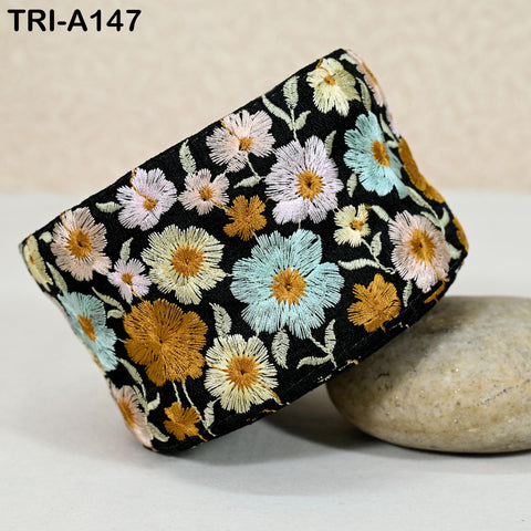 a black and white floral embroidered piece of fabric, with a variety of colorful flowers and leaves. The fabric appears to be a decorative accessory, possibly a headband or a piece of clothing.