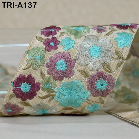 a decorative fabric with a floral pattern, including various shades of green, purple, and white flowers. The fabric appears to be a ribbon or a piece of cloth with a floral design.