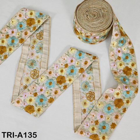 a roll of floral embroidered fabric and a spool of the same fabric, both placed on a white background.
