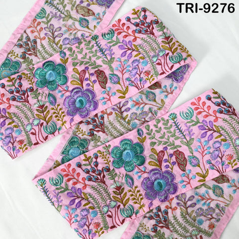 a pink fabric with a floral pattern, including various types of flowers and leaves in different colors such as purple, green, and blue. The fabric appears to be embroidered or sewn, with intricate details and designs.