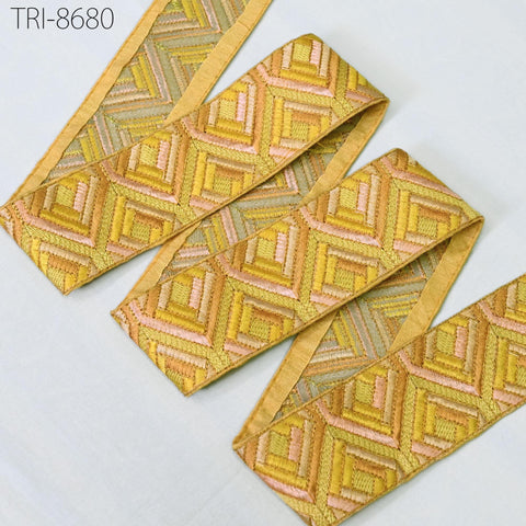 a set of decorative fabric pieces with a geometric pattern in shades of yellow and pink. The fabric appears to be made of a shiny material and is arranged in a way that creates a visually appealing design.