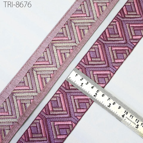 a close-up view of a decorative trim with a geometric pattern in shades of pink and purple. A ruler is placed next to the trim, indicating its size.