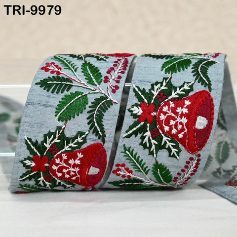 a decorative ribbon with a floral pattern in shades of green and red, including red and white flowers and leaves. The ribbon appears to be made of a fabric material, possibly denim, and is displayed on a white surface.