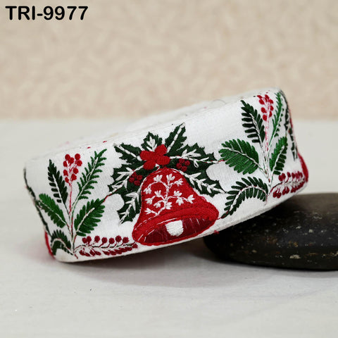A white fabric with a red bell and green leaves design, placed on a black surface.