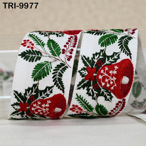 two rolls of ribbon with a floral pattern, including red berries, green leaves, and red bells.
