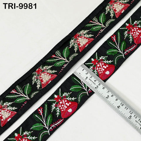 a close-up view of a decorative black ribbon with a floral pattern in red and green colors. A ruler is placed on the ribbon, indicating its size.