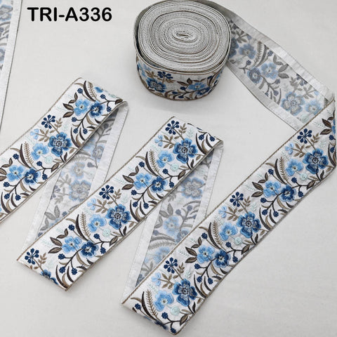 a roll of fabric with a floral pattern, including blue and white flowers, and a spool of thread with a similar floral pattern.