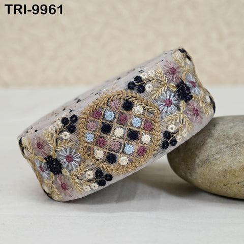 a decorative fabric with a floral pattern, including a central circular design surrounded by smaller floral and leaf motifs. The fabric appears to be a piece of embroidery or a decorative textile.