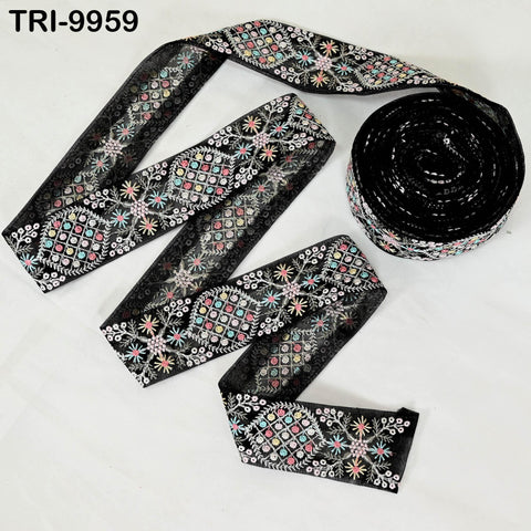 a spool of black embroidery ribbon with a floral pattern, and a smaller spool of the same ribbon with a different floral pattern.