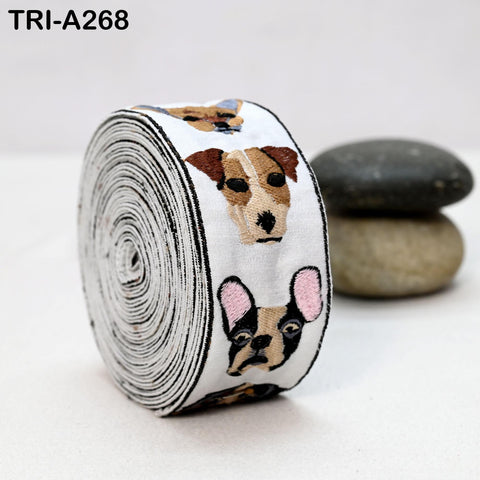 A roll of ribbon with dog faces printed on it, placed on a white surface next to some rocks.