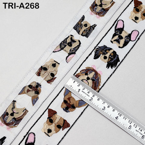 a white fabric with a repeating pattern of dog faces, including a variety of breeds and colors. A ruler is placed on the fabric, likely for measuring the size or dimensions of the pattern.