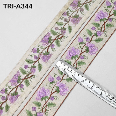 a close-up view of a decorative fabric with a floral pattern, featuring purple flowers and green leaves. A ruler is placed on the fabric, indicating its size or dimensions.