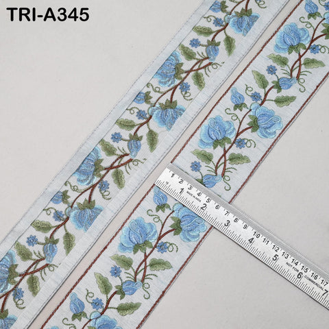 a decorative fabric with a floral pattern, featuring blue flowers and leaves. A ruler is placed on the fabric, indicating the size or dimensions of the pattern.